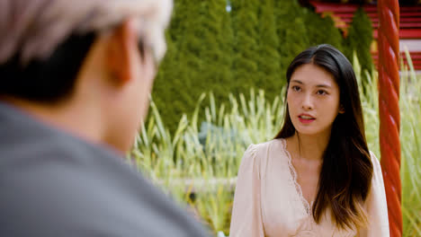 Rear-view-of-man-talking-with-japanese-woman-on-a-japanese-garden-porch-garden-while-they-drinking-tea