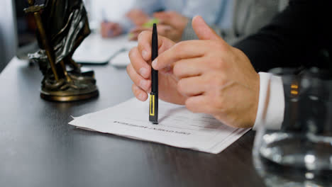 Close-up-view-of-the-hands-of-caucasian-man-holding-pencil-on-a-document-at-a-table