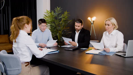 Camera-zoom-out-on-a-group-of-multiethnic-legal-advisors-talking-and-reading-documents-sitting-at-a-table-in-the-office