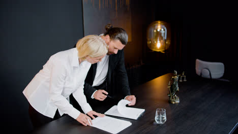 Caucasian-legal-advisors-talking-and-reading-documents-standing-close-at-a-table-in-the-office