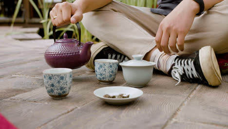 Hände-Eines-Japaners,-Der-In-Einem-Japanischen-Garten-Sitzt-Und-Tee-In-Tassen-Gießt