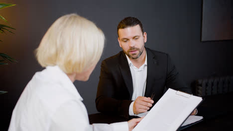 Close-up-view-of-caucasian-legal-advisors-talking-and-reading-documents-sitting-at-a-table-in-the-office