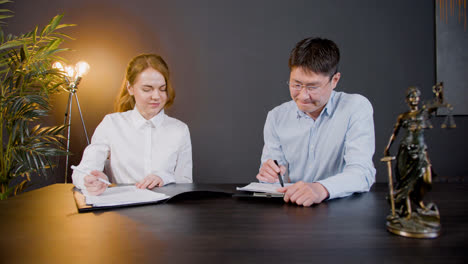 Front-view-of-multiethnic-legal-advisors-talking-and-reading-documents-at-a-table-in-the-office