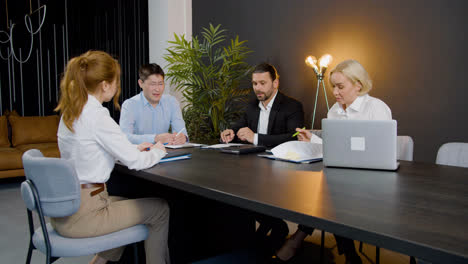 Group-of-multiethnic-legal-advisors-talking-and-reading-documents-sitting-at-a-table-in-the-office