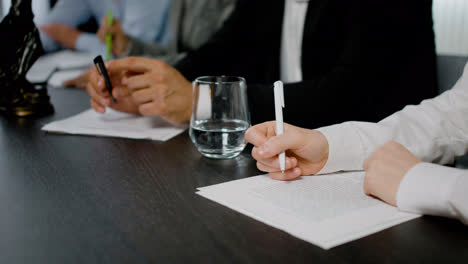 Close-up-view-of-the-hands-of-caucasian-woman-holding-pencil-on-a-document-at-a-table