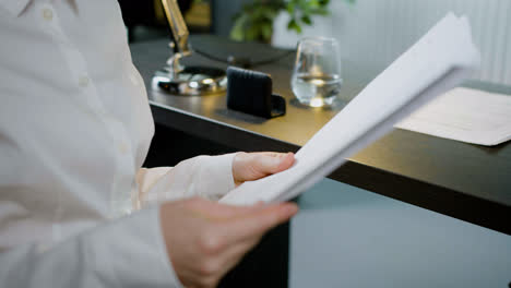 Close-up-view-of-the-hands-of-caucasian-woman-holding-a-document-sitting-in-the-office