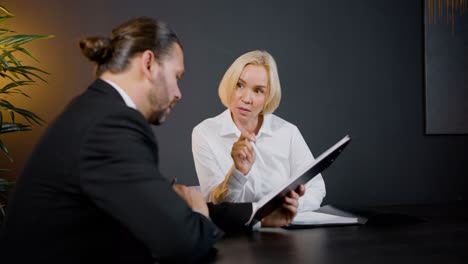 Close-up-view-of-caucasian-legal-advisors-talking-and-reading-documents-sitting-at-a-table-in-the-office