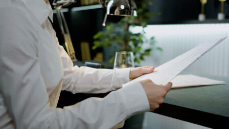 Close-up-view-of-the-hands-of-caucasian-woman-holding-a-document-sitting-in-the-office