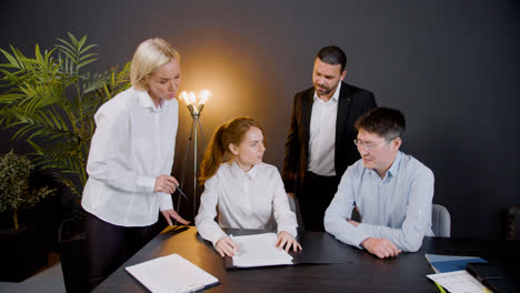 Ginger-woman-reading-a-document-sitting-at-table-in-the-office-while-legal-advisors-explain-her-the-process