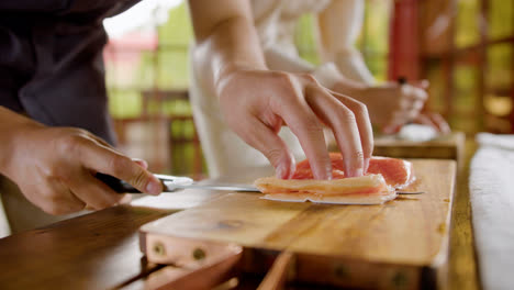 Close-up-view-of-hands-of-a-man-cutting-fresh-fish-on-top-of-a-kitchen-board