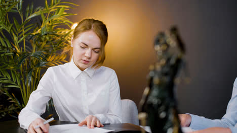 Caucasian-female-legal-advisor-and-asian-man-reading-documents-and-talking-at-a-table-in-the-office