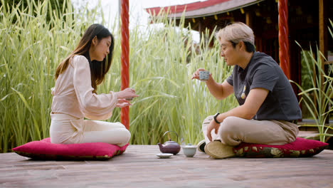 Japanese-couple-sitting-on-cushions-on-a-japanese-garden-porch-having-tea-and-talking