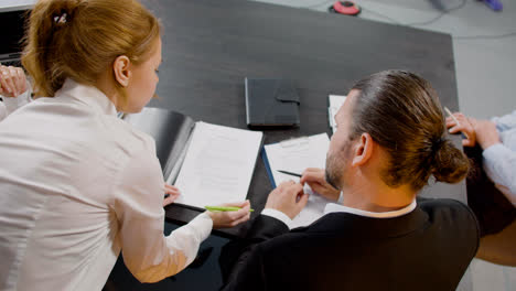 Top-view-of-caucasian-legal-advisors-talking-and-reading-documents-sitting-at-a-table-in-the-office