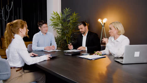 Group-of-multiethnic-legal-advisors-talking-and-reading-documents-sitting-at-a-table-in-the-office