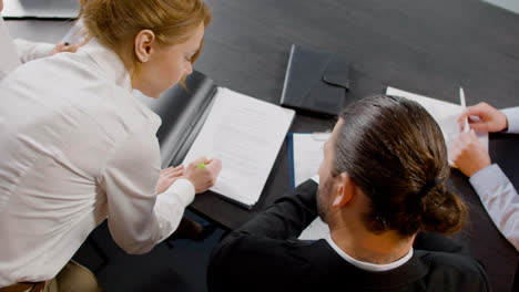 Top-view-of-caucasian-legal-advisors-talking-and-reading-documents-sitting-at-a-table-in-the-office