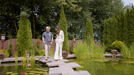 Japanese-couple-walking-over-the-bridge-of-a-Japanese-garden.-They-stop-on-the-porch