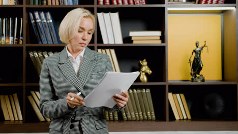 Kaukasische-Rechtsberaterin-In-Eleganter-Kleidung-Beim-Lesen-Von-Dokumenten,-Während-Sie-Im-Büro-Steht