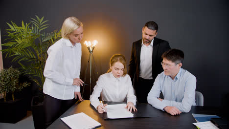 Ginger-woman-reading-a-document-sitting-at-table-in-the-office-while-legal-advisors-explain-her-the-process