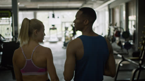 Rear-view-of-caucasian-female-monitor-and-an-athletic-african-american-man-in-the-gym.