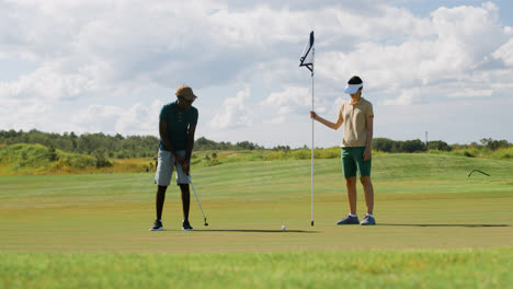 Hombre-Afroamericano-Y-Mujer-Caucásica-Practicando-Golf-En-El-Campo-De-Golf.