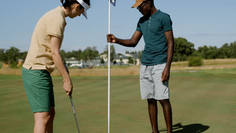 Hombre-Afroamericano-Y-Mujer-Caucásica-Practicando-Golf-En-El-Campo-De-Golf.