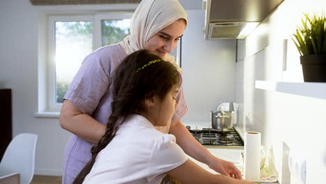 Side-view-of-mother-with-hiyab-and-daughter-in-the-kitchen.