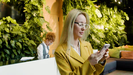 Blonde-woman-using-smartphone-in-a-hotel