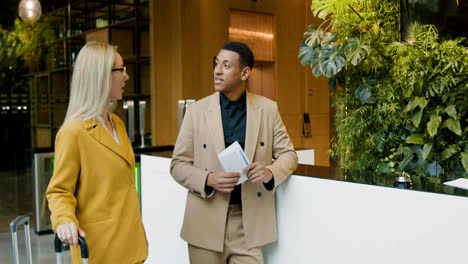 Blonde-woman-and-african-american-man-talking-in-a-hotel