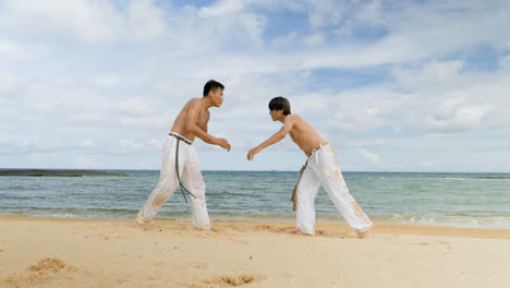 Dos-Hombres-Bailando-Capoeira-En-La-Playa