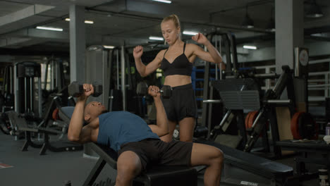 Caucasian-female-monitor-and-an-athletic-african-american-man-in-the-gym.