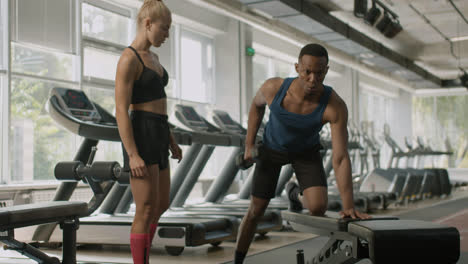 Front-view-of-caucasian-female-monitor-and-an-athletic-african-american-man-in-the-gym.