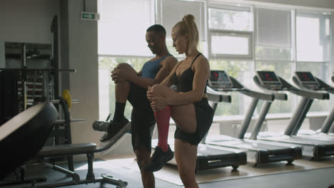Side-view-of-caucasian-female-monitor-and-an-athletic-african-american-man-in-the-gym.