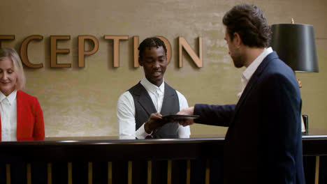 Young-man-receiving-his-room-key-at-the-hotel