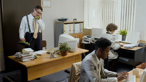 Caucasian-businessman-working-stading-near-his-desk-and-talking-on-the-phone-in-a-vintage-office.