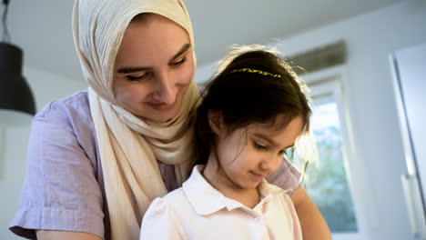 Close-up-view-of-mother-with-hiyab-and-daughter-in-the-kitchen.
