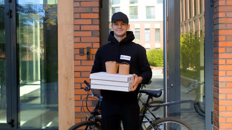 Young-man-holding-pizza-boxes-on-the-entrance-of-the-building