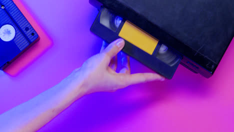 Top-view-of-video-VHS-device-and-cassette-on-lilac-background