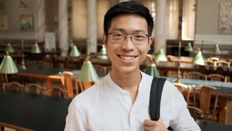 Junger-Asiatischer-Männlicher-Student,-Der-In-Der-Bibliothek-In-Die-Kamera-Lächelt