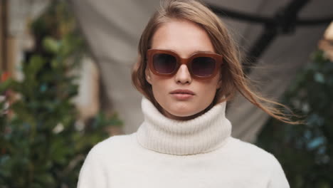 Caucasian-female-wearing-sunglasses-and-sweater-outdoors.