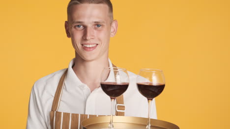 Smiling-waiter-giving-ok-sign-and-serving-red-wine