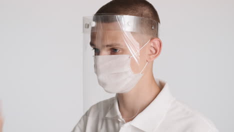 Mann-Trägt-Transparente-Schutzmaske-über-Weißer-Gesichtsmaske