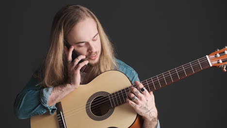 Caucasian-young-man-with-guitar-having-a-call-on-smartphone.