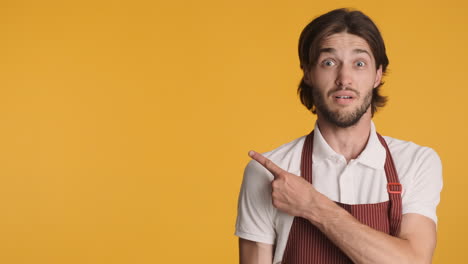 Caucasian-waiter-in-front-of-camera-on-yellow-background.