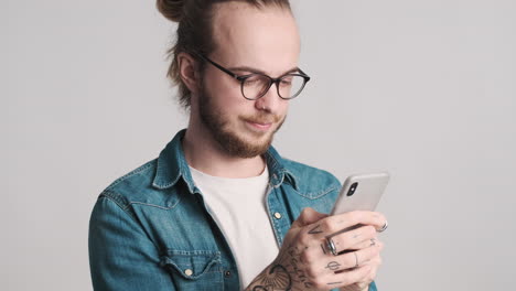 Caucasian-young-man-texting-on-smartphone-on-camera.