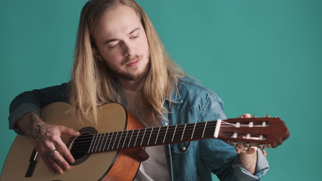 Caucasian-young-man-tuning-the-guitar-on-camera.