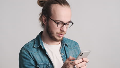 Caucasian-young-man-texting-on-smartphone-on-camera.