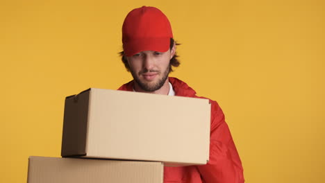 Caucasian-delivery-man-in-front-of-camera-on-yellow-background.