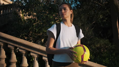 Soccer-woman-with-backpack-playing-with-a-ball-in-hands.