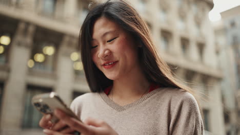 Mujer-Asiática-Joven-Sonriendo-Y-Mirando-A-La-Cámara-Al-Aire-Libre.