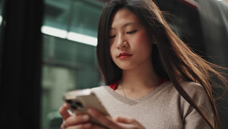 Young-Asian-woman-using-mobile-outdoors.